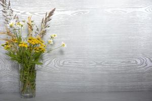 um buquê de flores silvestres em um vaso de vidro sobre uma mesa de madeira com um lugar vazio para o texto foto