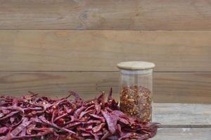 pimenta seca na mesa de madeira e flocos de pimenta em pote, especiarias foto