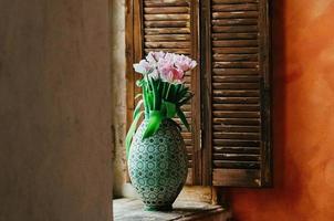 um buquê de flores em foco suave em um vaso no parapeito de uma janela