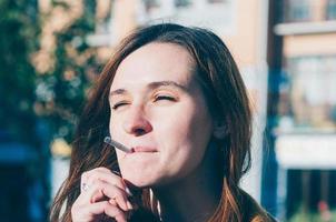 mulher muito fofa fumando um cigarro na rua foto