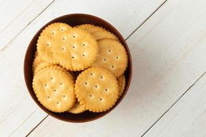 biscoitos de bolacha arredondados em uma tigela de madeira na mesa de madeira branca foto