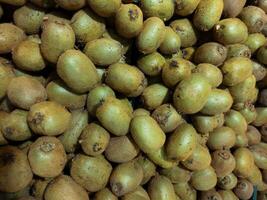 a terra tesouros, kiwis closeup, kiwi fruta dentro a mercado, um pilha do todo kiwi frutas em a contador dentro a supermercado Como fundo, textura, marrom kiwi frutas empilhado dentro pilha, kiwi fruta fundo foto