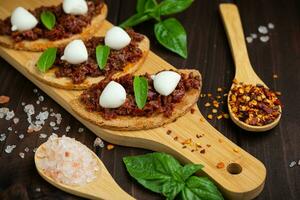 bruschetta com tomate seco, mussarela, alho e azeite. sanduíche de cozinha italiana tradicional feita de ciabatta grelhado. antipasti foto