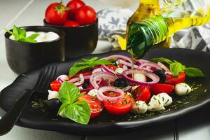 caprese salada com tomates mozzarella azeitonas manjericão e Oliva óleo em de madeira mesa. foto