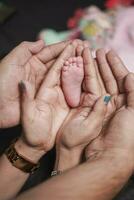 a pequeno pernas do uma recém-nascido bebê dentro a mãos do dele mãe e Papai. a conceito do maternidade e infância foto