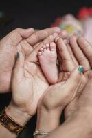 a pequeno pernas do uma recém-nascido bebê dentro a mãos do dele mãe e Papai. a conceito do maternidade e infância foto