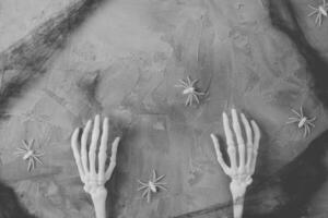 dia das Bruxas cinzento fundo com esqueleto mãos, espiga rede e aranhas. feliz dia das Bruxas bandeira brincar foto