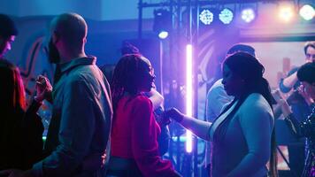 jovem casais valsa às Boate, dançando dentro pares em lento música em dança chão. feliz romântico parceiros desfrutando valsa às discoteca, tendo Diversão com holofotes e álcool. festa. foto