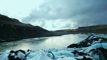 zangão tiro do vatnajokull geleira boné dentro Islândia, lindo gelo blocos com maciço fenda por aí Nevado montanhas. majestoso gelado icebergs flutuando em congeladas lago. lento movimento. foto