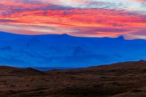 islandês frio Planalto com deslumbrante pôr do sol, conceito para noite fotografia. tirar o fôlego Visão do rosado algodão doce gostar céu vencimento para Sol configuração acima grande nórdico montanha gamas. foto