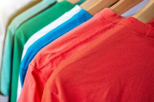 moda camiseta em roupas prateleira - fechar-se do brilhante colorida armário de roupa em de madeira cabides dentro loja armário. foto