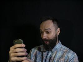homem com barba e bigode olhando para um telefone celular