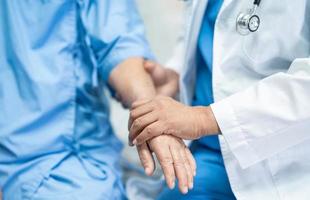 médico segurando mãos comoventes paciente asiática sênior com amor