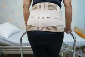 paciente senhora asiática usando cinto de suporte para dor nas costas foto