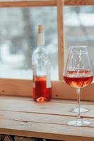 uma imagem vertical de uma garrafa de vinho rosé e duas taças foto
