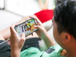 mão criança segurando smartphone para jogar jogo online em casa foto