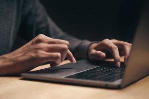 homem usando um laptop na mesa de madeira, internet, pesquisando, navegando foto