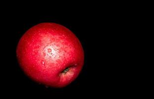 gota de água na superfície brilhante de maçã vermelha em fundo preto