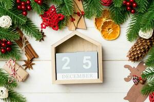 vista superior de galhos de árvores do abeto em fundo de madeira. calendário decorado com brinquedos festivos. dia vinte e cinco de dezembro. conceito de tempo de natal foto