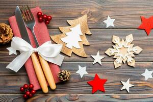 vista superior do jantar de ano novo em fundo de madeira. talheres festivos em guardanapo com enfeites de natal e brinquedos. close-up do conceito de férias em família foto