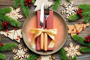 vista superior de talheres e prato em fundo de madeira festivo. conceito de jantar em família de ano novo. abeto e decorações de natal foto