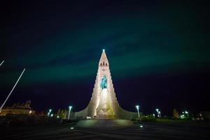 luzes do norte brilhando sobre a igreja em reykjavik foto