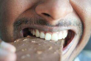 jovem comendo chocolate amargo close-up foto