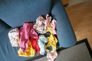 bagunçado roupas em sofá às casa foto