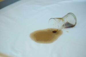 copo do café derramado em cama foto