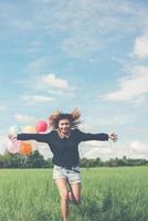 jovem segurando um balão na pastagem verde, correndo e aproveitando o ar fresco foto
