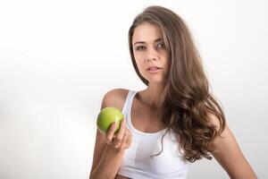 bela mulher segurando uma maçã verde enquanto isolada no branco foto