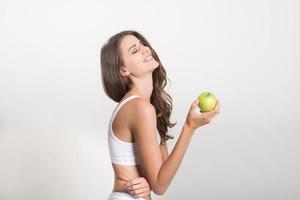 bela mulher segurando uma maçã verde enquanto isolada no branco foto