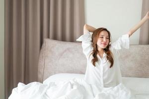 retrato linda mulher asiática acordar na cama pela manhã foto