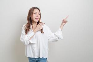 retrato de uma bela mulher asiática com a mão apresentando ou apontando no fundo branco foto