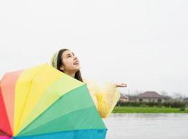 linda mulher morena segurando guarda-chuva colorido na chuva foto