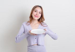 retrato linda mulher asiática segurando um prato vazio no fundo branco foto