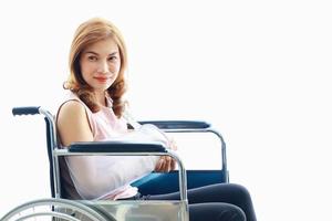Mulher asiática com um braço quebrado usando gesso na cadeira de rodas foto