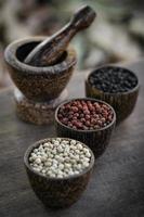 grãos de pimenta preta e vermelha branca orgânica em exposição de madeira foto