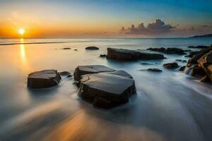 uma grandes exposição fotografia do pedras em a de praia às pôr do sol. gerado por IA foto