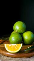 laranja fruta com verde casca, metade papel, e fatia com Sombrio humor fotografia. vertical, retrato, Móvel telefone papel de parede foto
