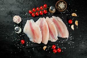 cru peixe filé com especiarias e tomates em uma pedra borda. foto