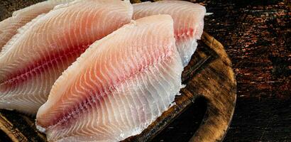 cru peixe filé em uma de madeira corte borda. foto