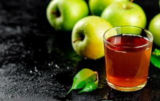 uma vidro do verde maçã suco com folhas em a mesa. foto