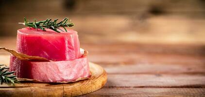 uma bife do cru atum em uma corte borda com uma raminho do alecrim. foto