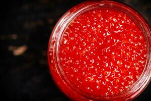 vermelho caviar dentro uma vidro jar. contra uma Sombrio fundo. foto