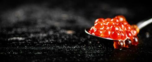 vermelho caviar dentro uma colher em a mesa. foto