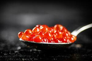 vermelho caviar dentro uma colher em a mesa. foto