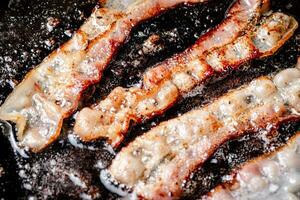 peças do bacon estão frito dentro ebulição óleo com ar bolhas. foto