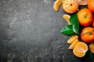 maduro tangerinas com folhagem. em uma Preto fundo. foto