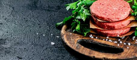 cru hamburguer em uma de madeira corte borda com salsinha. foto